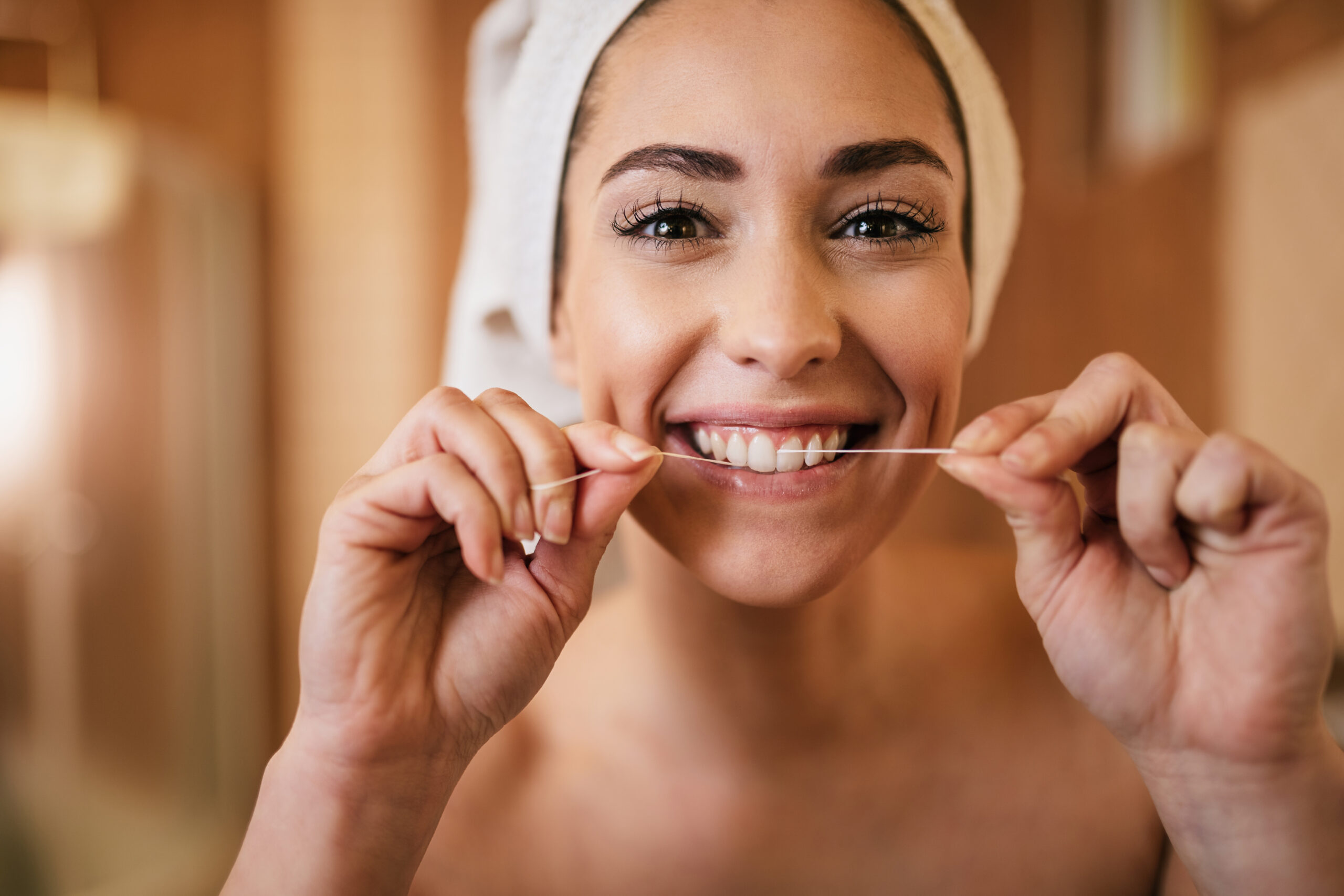 A woman flossing her teeth, highlighting a crucial aspect of daily Oral Hygiene for a Healthy Mouth and Body in Beverly Hills.