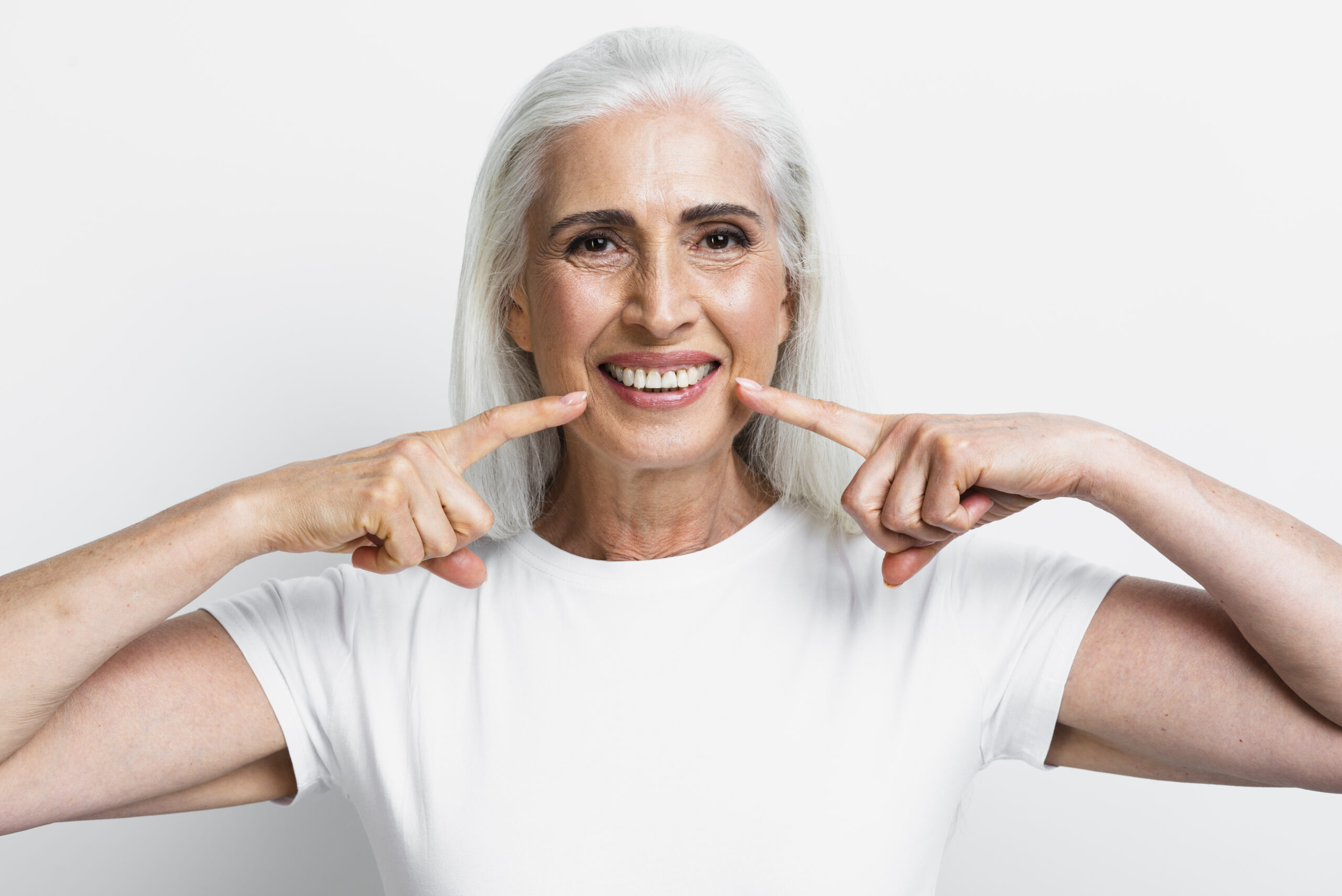 An elderly woman smiling brightly, showing her perfectly restored teeth, indicative of successful dental implants, relevant to Dental Implant Facts in Beverly Hills.