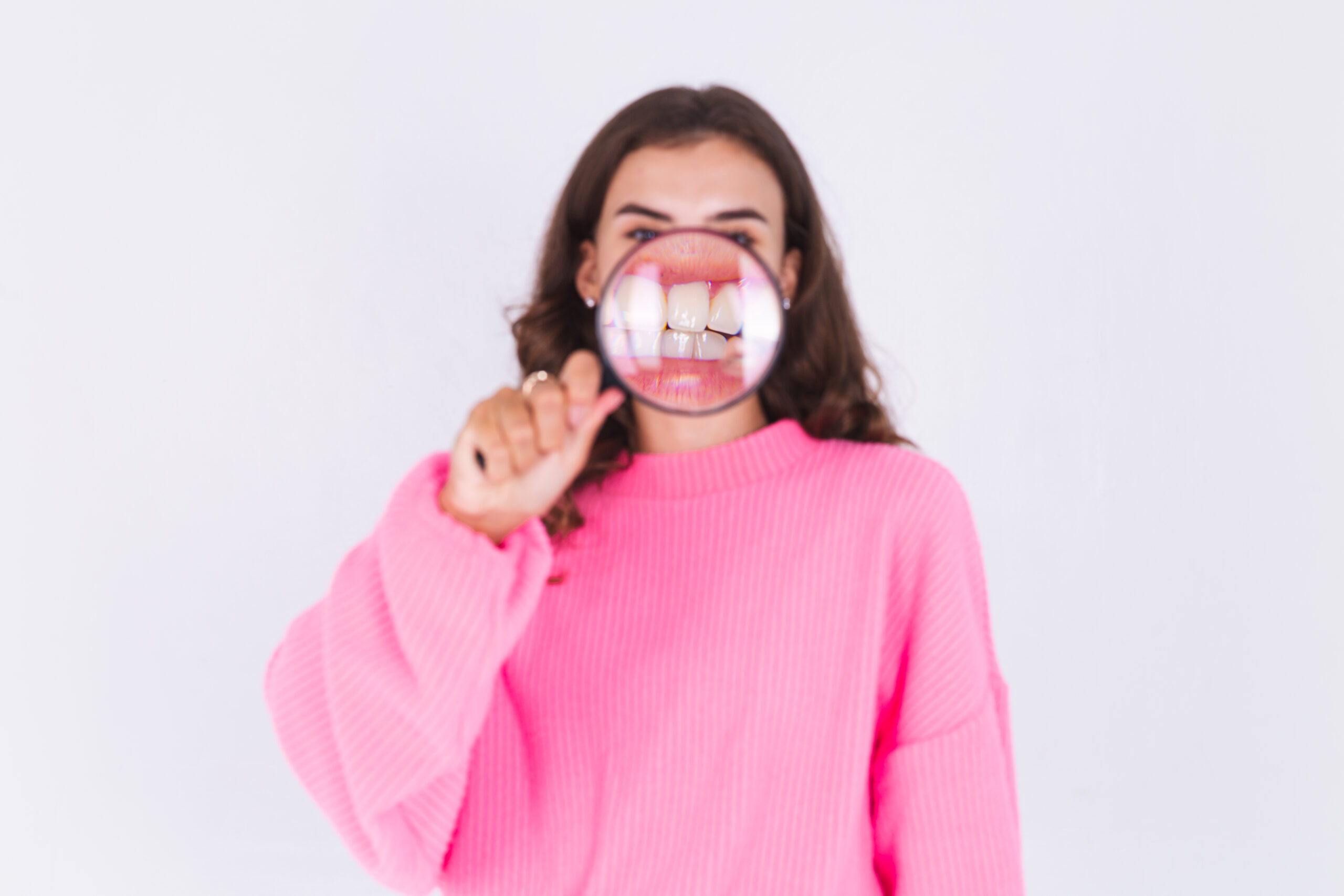 Magnifying glass on teeth: understand Gingivitis vs. Periodontitis for gum health in Beverly Hills.